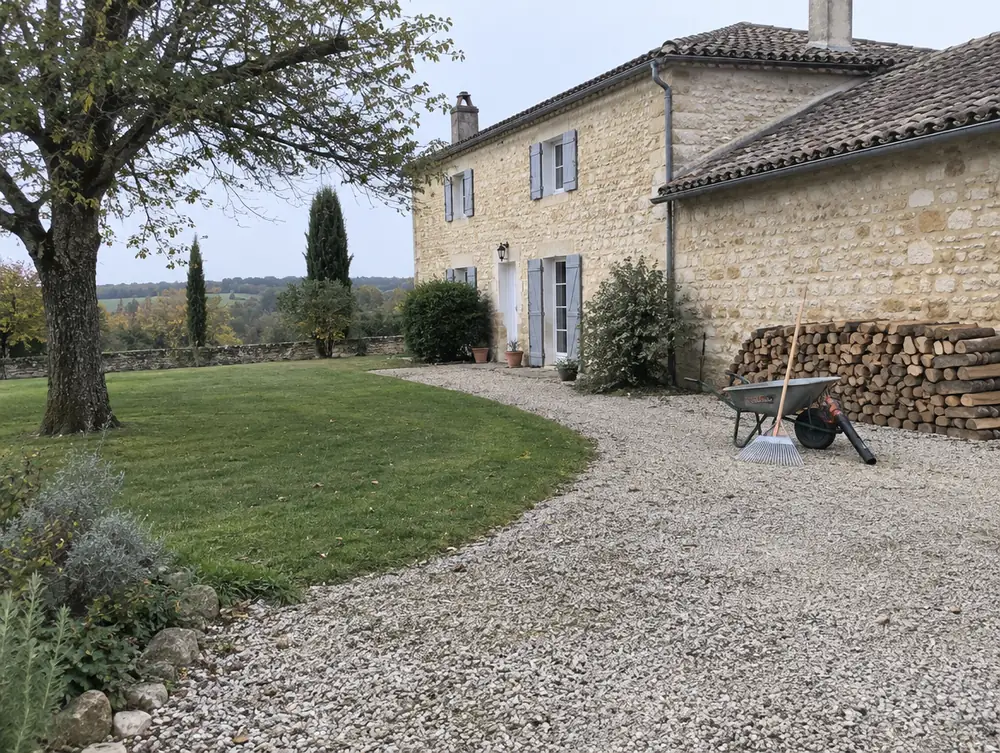 Cour ratissée et bûches rangées devant une maison gasconne après le chantier